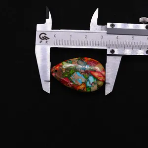 Macro view of colorful teardrop synthetic stone pendant measured with a caliper