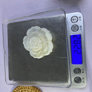 Vue détaillée montrant le poids d'un pendentif cygne en nacre sculptée sur une balance précise