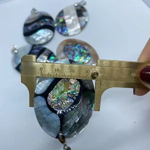 Dettaglio del ciondolo in conchiglia abalone misurato con calibro per dimensioni reali