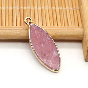Detalle de un colgante marquise de piedra natural rosa con borde de metal dorado