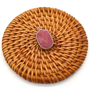 Detail of red agate oval stone pendant with silver-plated rim on a woven mat