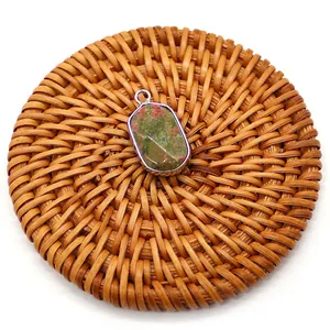 Detail shot of faceted natural Unakite stone pendant with silver-plated edge on rattan mat