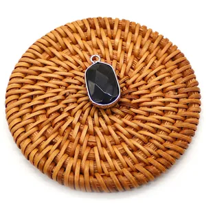 Macro shot of faceted black stone pendant with silver plated bezel on woven rattan mat