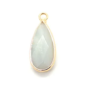 Macro view of teardrop natural stone pendant with gold faceted metal edge and ring