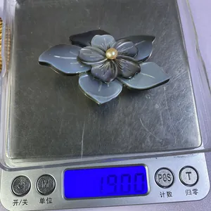 Vue macro du pendentif fleur en nacre sur balance affichant un poids de 19,00g
