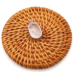 Detailed top view of natural oval crystal pendant with silver plated edge on woven mat