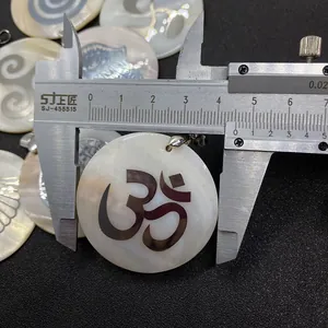 Vue macro mesurant le diamètre de 45 mm du pendentif en nacre avec symbole Om
