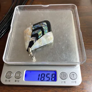 Vista macro di un ciondolo a rombo in conchiglia da 18,58 g su una bilancia di precisione