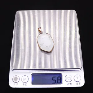 Macro shot of a faceted white stone pendant with gold edges weighing 5.8g on a scale