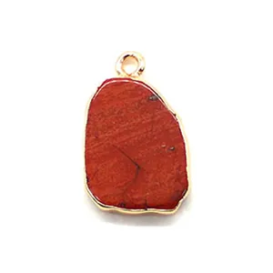 Macro detail of red natural stone pendant with irregular shape and gold plated edge