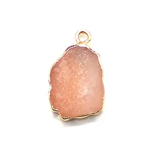 Close-up of pink druzy quartz pendant with gold plated irregular edges and metal bail