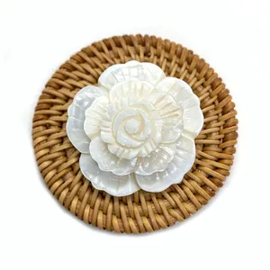 Pendentif fleur de cygne en coquillage naturel avec sculpture 3D sur un tapis tissé