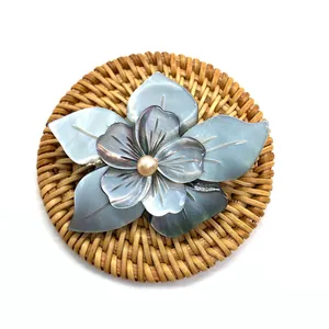 Élégant pendentif fleur en coquillage naturel avec perle jaune centrale sur tapis tressé
