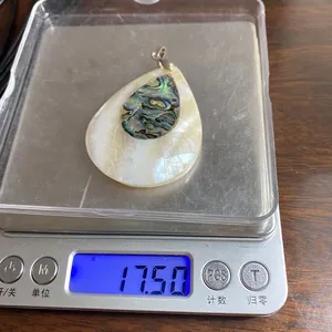 Pendaglio a goccia in madreperla e abalone pesato su una bilancia digitale professionale