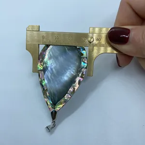 Vista ravvicinata di un ciondolo in abalone da 34mm misurato con un calibro in ottone