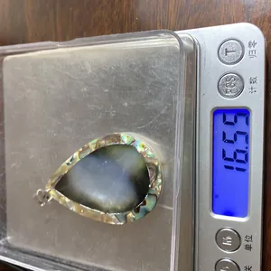 Misurazione del peso di un ciondolo a goccia in conchiglia di abalone e nera su scala