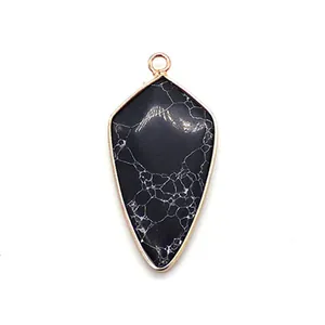 Détail d'un pendentif en pierre noire en forme de balle avec marbrures et bordure dorée