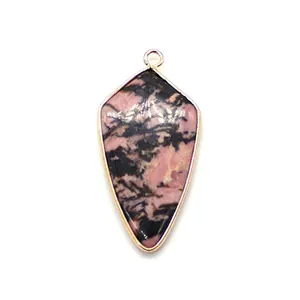 Vue macro d'un pendentif en pierre naturelle rose en forme de bouclier avec cadre doré