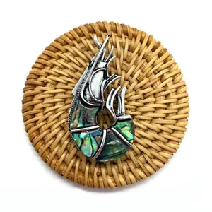 Macro detail van een garnaalvormige broche met iriserende parelmoer inleg op zilver metaal