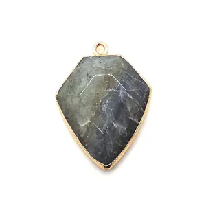 Macro shot of faceted shield-shaped natural stone pendant with electroplated gold edges