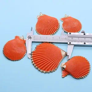 Vue détaillée montrant la taille de 5,4 cm des pendentifs coquillages orange avec bord doré