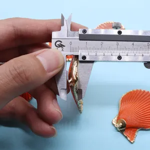 Mesure de l'épaisseur de 8mm d'un pendentif coquillage orange avec bordure dorée au pied