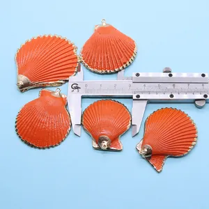Détail de 5 pendentifs coquillages orange avec bordure dorée sur un fond bleu clair
