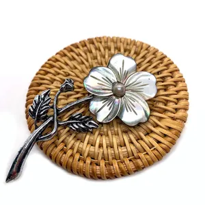 Detailed view of carved natural shell flower brooch with pearl center on woven coaster