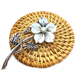 Macro detail of a vintage flower brooch with iridescent shell petals and a white pearl center