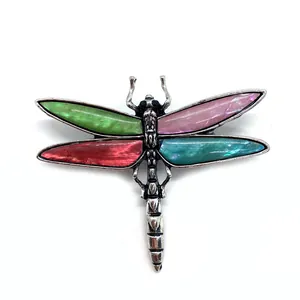 Detailed close-up of a dragonfly brooch with colorful seashell wings and silver texture