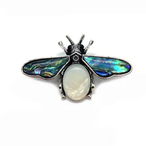 Detailed view of bee-shaped brooch with abalone shell wings and white gemstone body