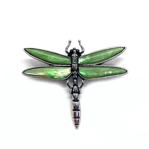 Silver dragonfly brooch featuring inlaid green natural sea shell wings in a vintage style