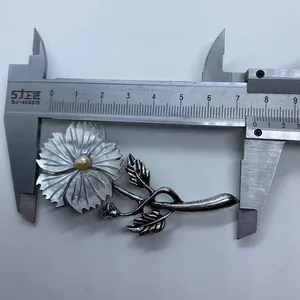 Detailed view of carved flower brooch with shell petals and pearl center, size 7.3cm