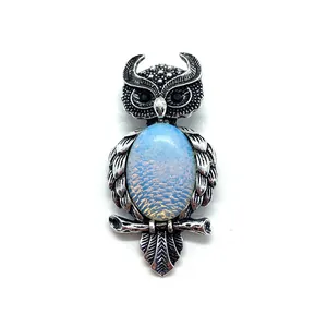 Macro shot of owl brooch with shell inlay and detailed silver feather textures