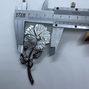 Macro view of flower brooch showing measurement of shell petals and center pearl