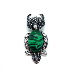 Macro detail of owl brooch with green malachite stone and vintage silver feather texture