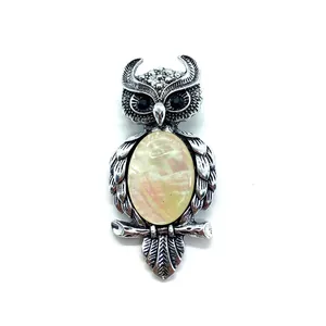 Macro detail of owl pendant with pink shell inlay and retro silver feather textures