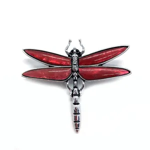 Vintage dragonfly brooch featuring shell-inlaid wings and a silver-tone metal finish