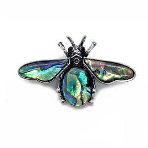 Close-up of iridescent abalone shell insect brooch with vintage silver finish