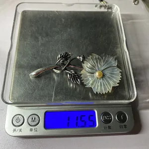 Detail shot showing a vintage flower brooch weighing 11.55 grams on a digital scale