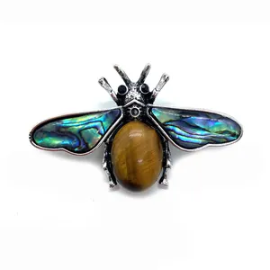 Macro detail of bee brooch featuring tiger eye stone body and abalone shell wings