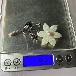 Detailed view of carved shell flower brooch weighing 9.32g on a digital scale