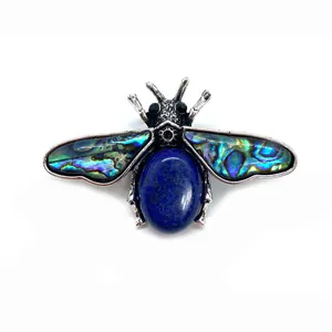 Detail of bee brooch featuring iridescent abalone shell wings and blue gemstone inlay