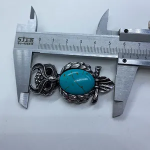 Detailed view of an owl brooch with turquoise stone measured with a caliper