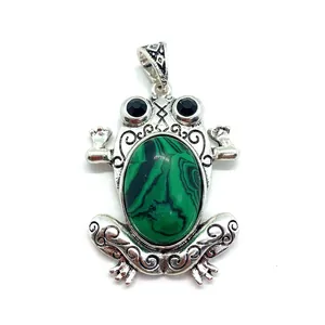 Macro detail of frog pendant featuring green stone and ornate silver carvings