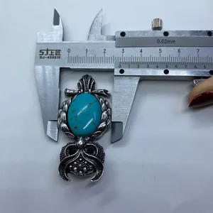 Macro shot measuring vintage owl pendant with green turquoise stone inlay width 2.7cm
