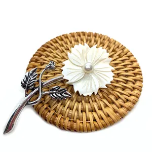 Exquisite flower brooch with white shell petals and pearl on a natural rattan base