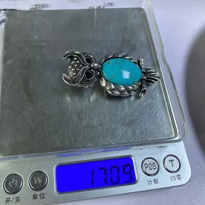 Macro detail of a retro owl pendant with green stone on an electronic scale weighing 17.09g