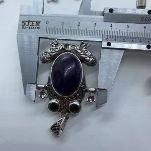 Detailed view of frog pendant with purple stone showing 5cm height on a caliper