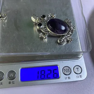 Detailed view of frog pendant weighing 18.26 grams on digital scale with purple gemstone